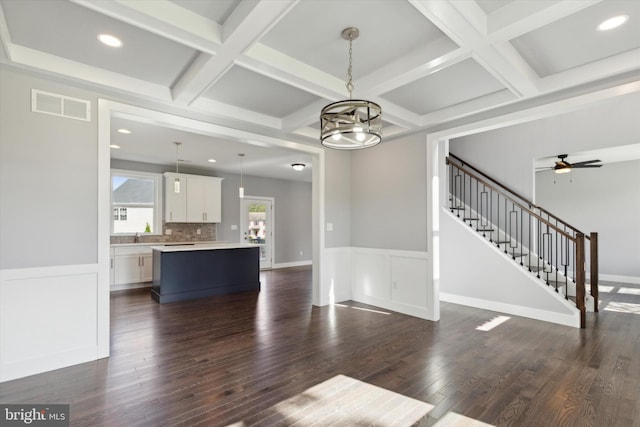 unfurnished living room with coffered ceiling, dark hardwood / wood-style flooring, beam ceiling, and a notable chandelier