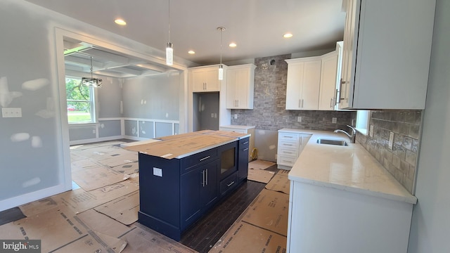 kitchen featuring tasteful backsplash, sink, a center island, white cabinetry, and butcher block counters