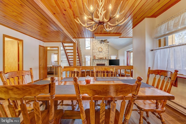 dining space with lofted ceiling, wood ceiling, hardwood / wood-style flooring, a fireplace, and ornamental molding