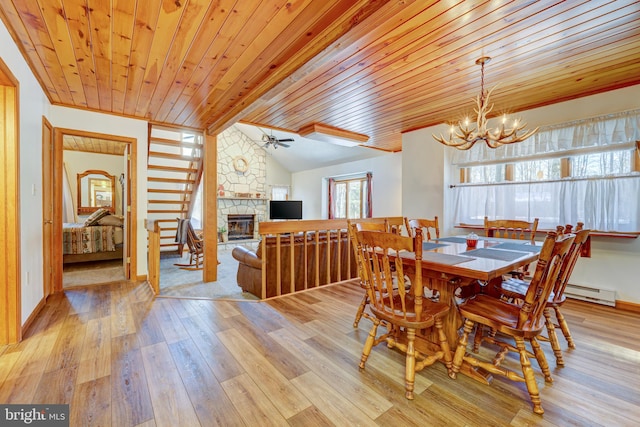 dining room with a baseboard heating unit, light wood-type flooring, a fireplace, ceiling fan with notable chandelier, and wooden ceiling