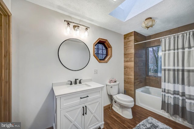 full bathroom featuring hardwood / wood-style flooring, a skylight, a textured ceiling, vanity, and toilet