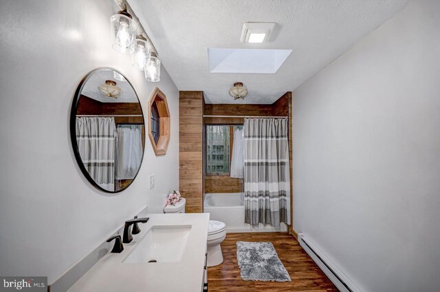 full bathroom featuring sink, hardwood / wood-style flooring, shower / bath combination with curtain, a skylight, and toilet