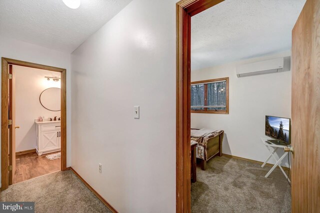 corridor featuring an AC wall unit, a textured ceiling, and carpet floors