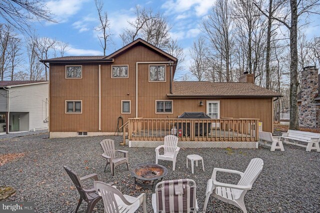 back of property with an outdoor fire pit and a deck