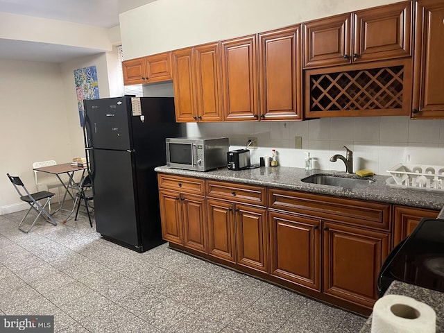 kitchen featuring sink, decorative backsplash, black fridge, and light tile patterned floors