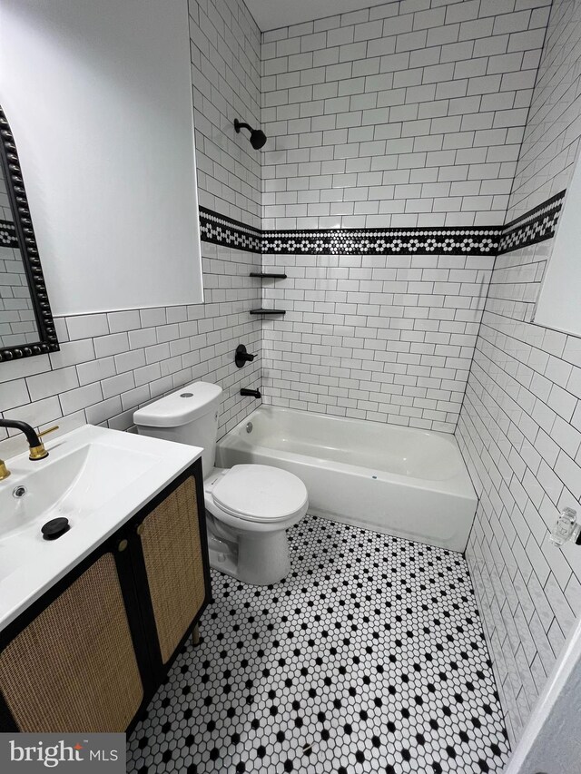 full bathroom featuring tiled shower / bath, tile walls, toilet, vanity, and tile patterned floors