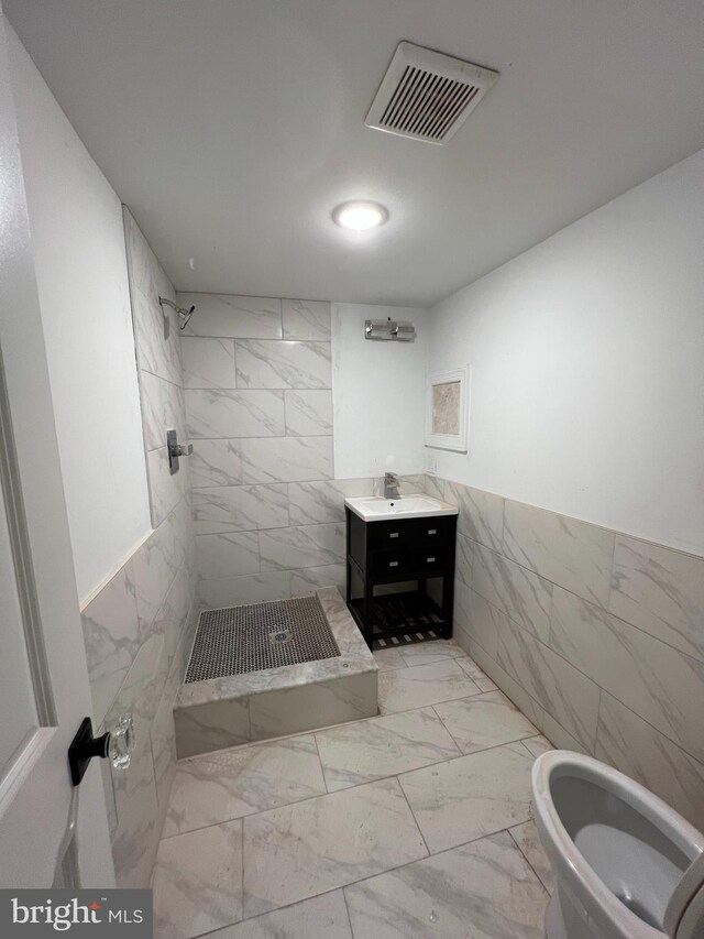 bathroom featuring vanity, tile walls, and tiled shower