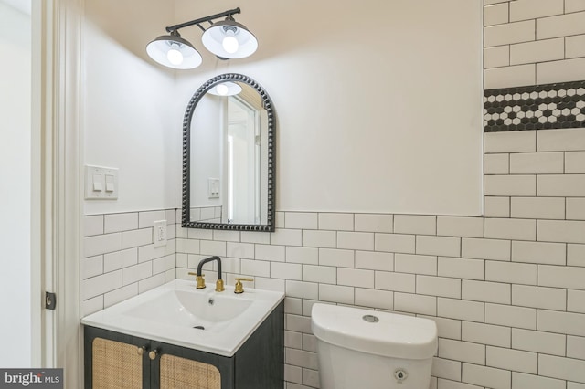 bathroom featuring toilet, vanity, and tile walls