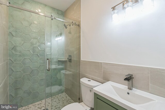 bathroom with toilet, an enclosed shower, vanity, and tile walls