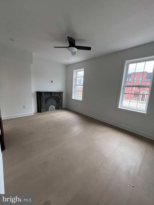 unfurnished living room with ceiling fan, light hardwood / wood-style floors, and a fireplace