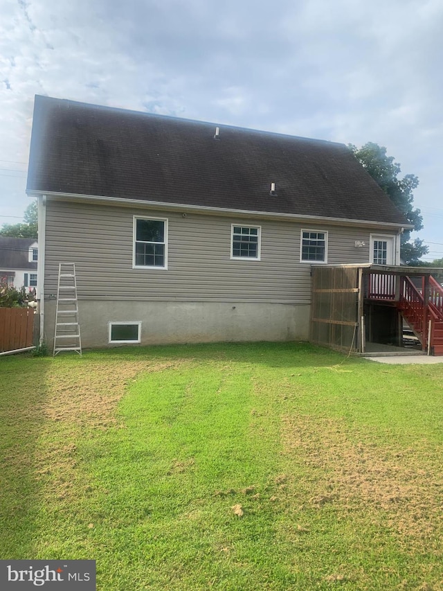 back of property with a wooden deck and a lawn