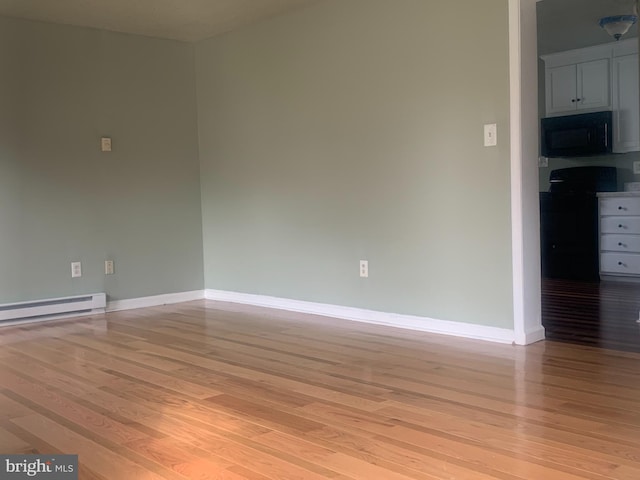 empty room featuring a baseboard heating unit and light hardwood / wood-style floors