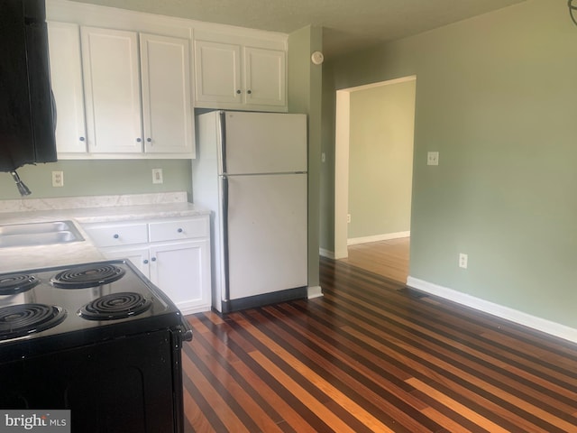 kitchen with black / electric stove, sink, white cabinets, and white refrigerator