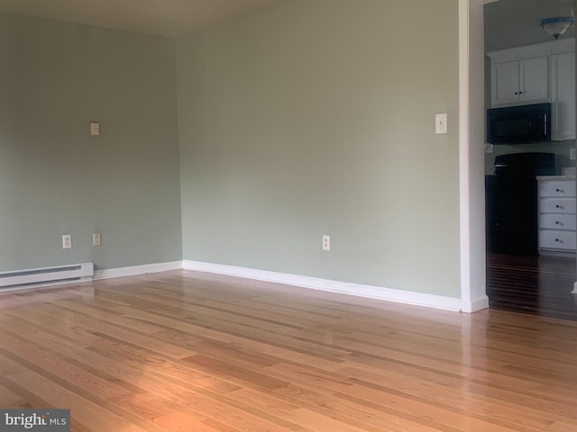 empty room with light hardwood / wood-style flooring and a baseboard radiator