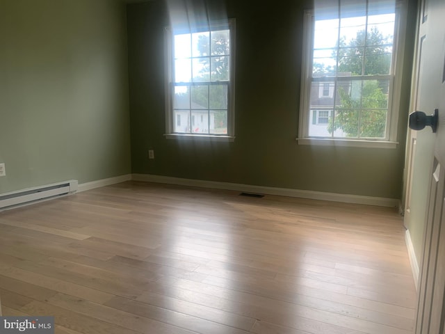 empty room with a baseboard heating unit and light hardwood / wood-style flooring