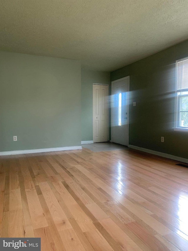 empty room featuring a textured ceiling and light hardwood / wood-style flooring