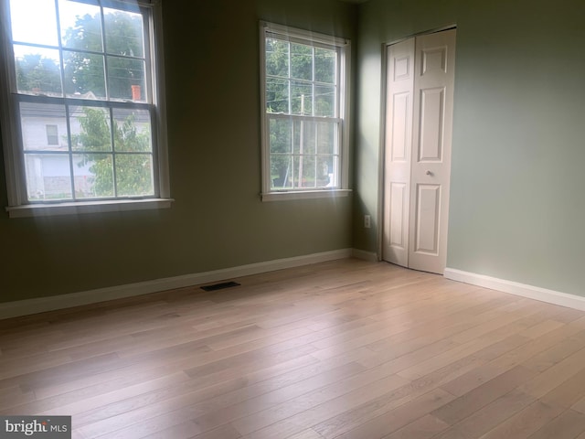 spare room featuring a wealth of natural light and light hardwood / wood-style floors