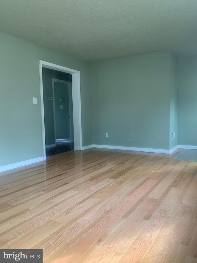 empty room featuring a textured ceiling and light hardwood / wood-style floors