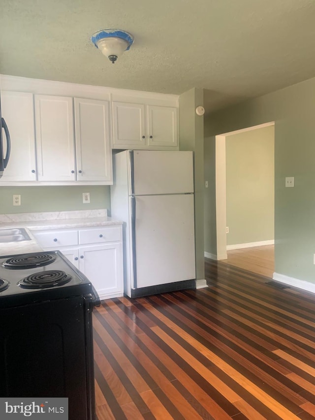 kitchen featuring range with electric cooktop, white cabinets, hardwood / wood-style floors, and white refrigerator