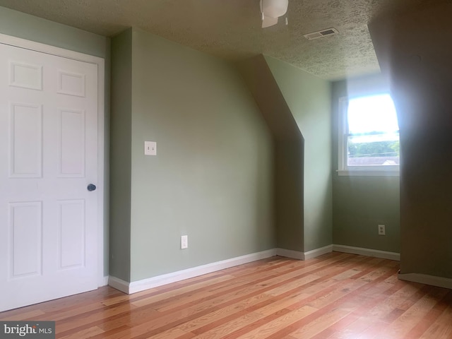 additional living space with ceiling fan, light hardwood / wood-style floors, and a textured ceiling