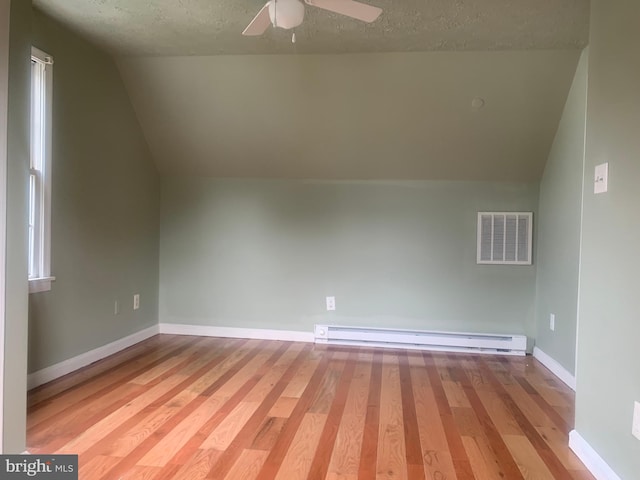 bonus room with light hardwood / wood-style flooring, ceiling fan, baseboard heating, a textured ceiling, and vaulted ceiling