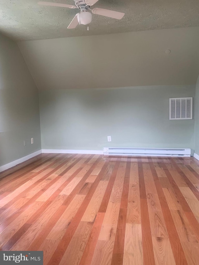 bonus room featuring a baseboard radiator, vaulted ceiling, a textured ceiling, and light wood-type flooring