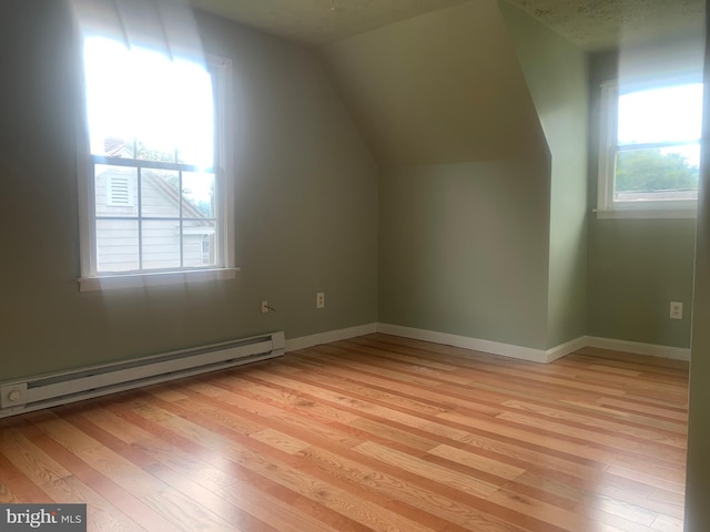 bonus room featuring lofted ceiling, a baseboard heating unit, and light hardwood / wood-style flooring