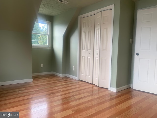 additional living space featuring a textured ceiling and light wood-type flooring