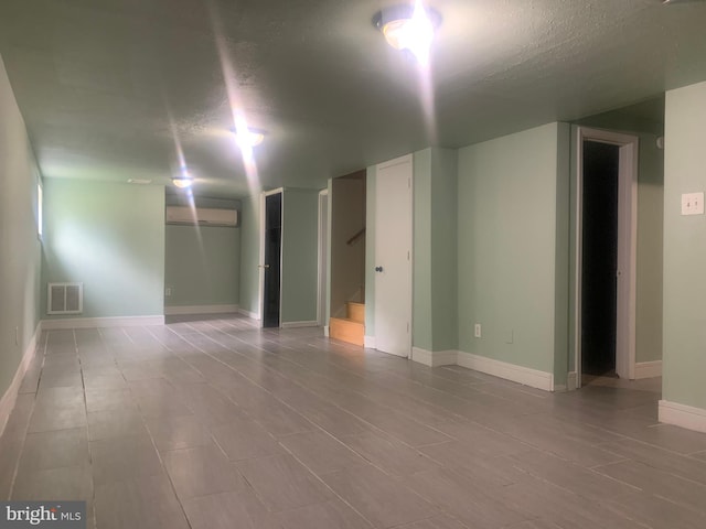 empty room with a wall mounted air conditioner and a textured ceiling