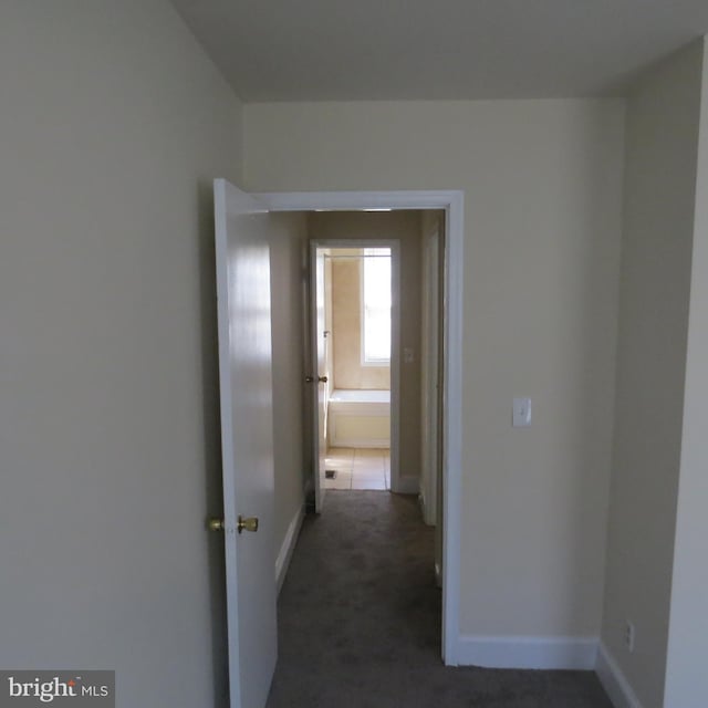 hall with dark colored carpet