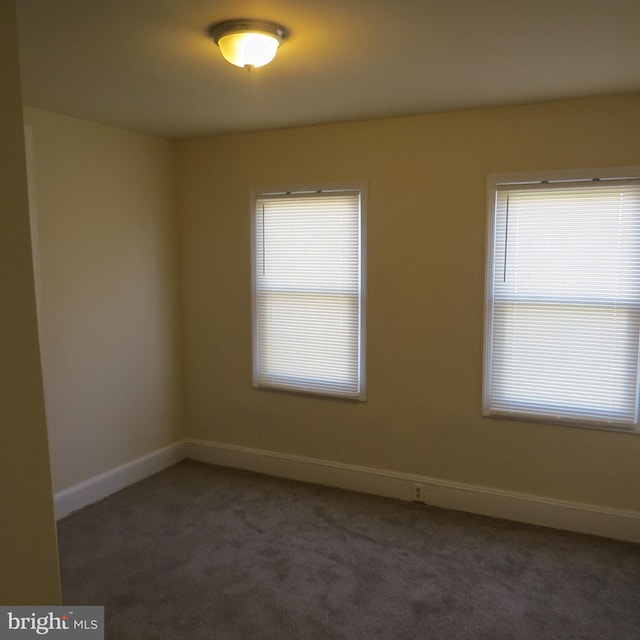 spare room featuring dark carpet