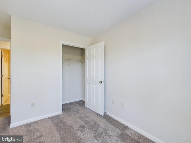 unfurnished bedroom with light colored carpet and a closet