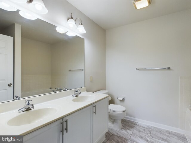 bathroom with toilet, a washtub, and vanity