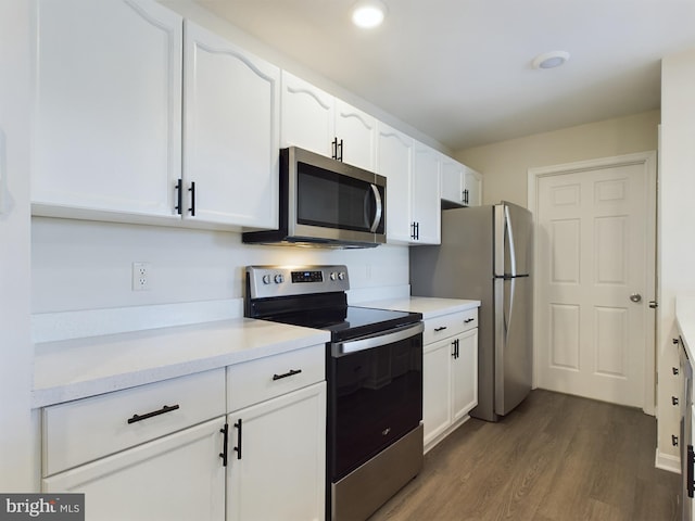 kitchen featuring stainless steel appliances, white cabinetry, and dark wood-type flooring