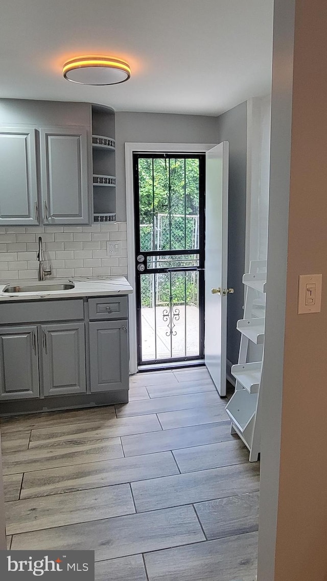 kitchen featuring gray cabinets, backsplash, sink, and light hardwood / wood-style flooring