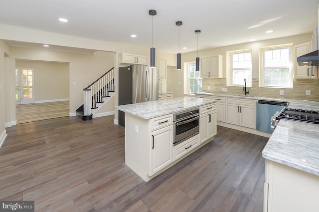 kitchen with dark hardwood / wood-style floors, a center island, appliances with stainless steel finishes, and decorative backsplash