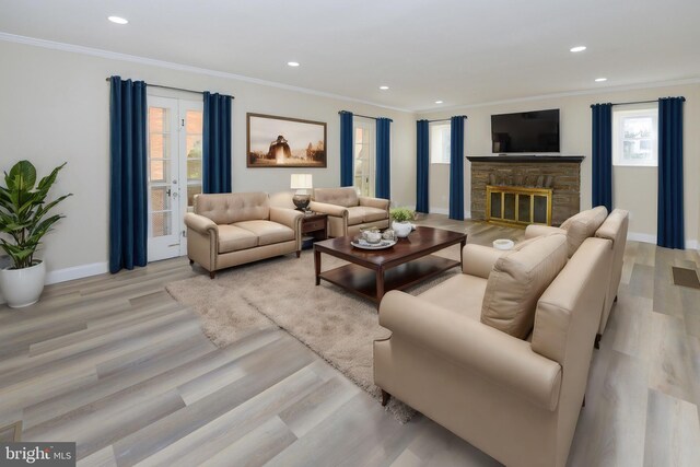 living room featuring light wood-type flooring, crown molding, and a stone fireplace