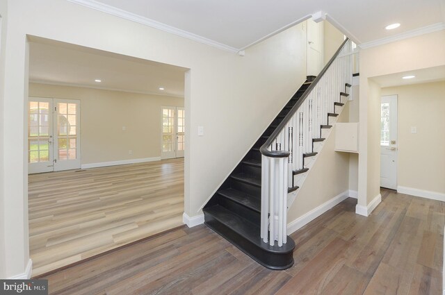 stairs with hardwood / wood-style flooring, ornamental molding, and french doors