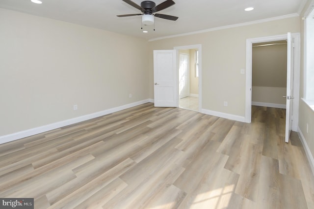 unfurnished bedroom with ceiling fan, light wood-type flooring, a walk in closet, a closet, and crown molding