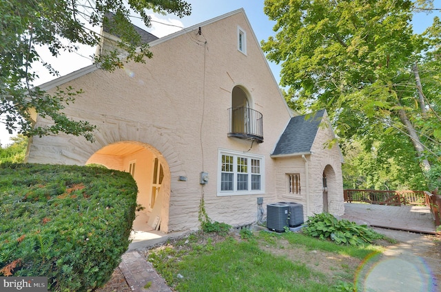 exterior space with a wooden deck, central AC unit, and a balcony