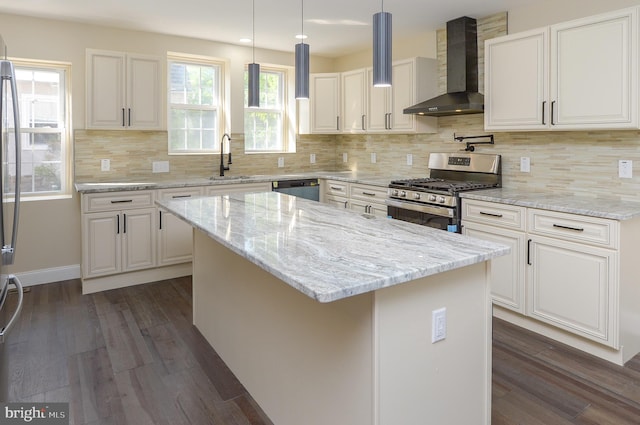 kitchen featuring appliances with stainless steel finishes, a center island, white cabinetry, and wall chimney exhaust hood