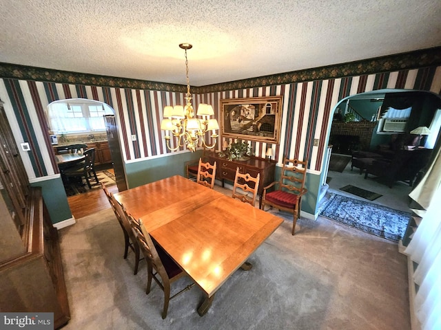 carpeted dining room with an inviting chandelier and a textured ceiling