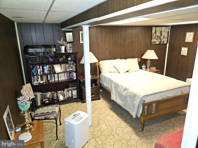 bedroom featuring wood walls and a paneled ceiling