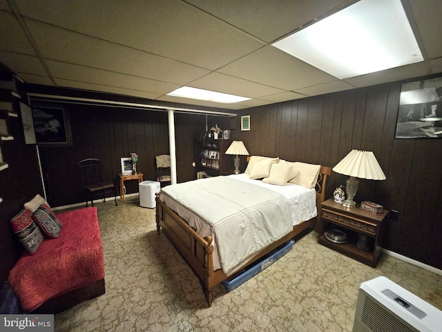 bedroom with a paneled ceiling and wooden walls