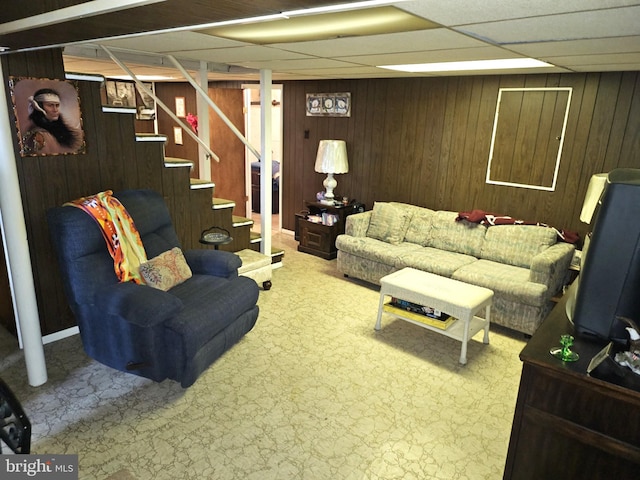 living room with a paneled ceiling and wood walls