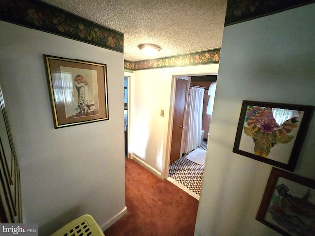 hallway featuring carpet flooring and a textured ceiling