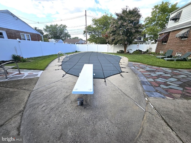 view of swimming pool with a diving board, a patio area, and a lawn