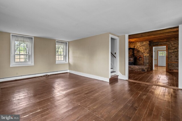 unfurnished room with a baseboard radiator, a stone fireplace, and hardwood / wood-style flooring