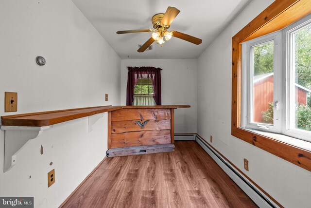 interior space featuring ceiling fan, a baseboard heating unit, and hardwood / wood-style flooring