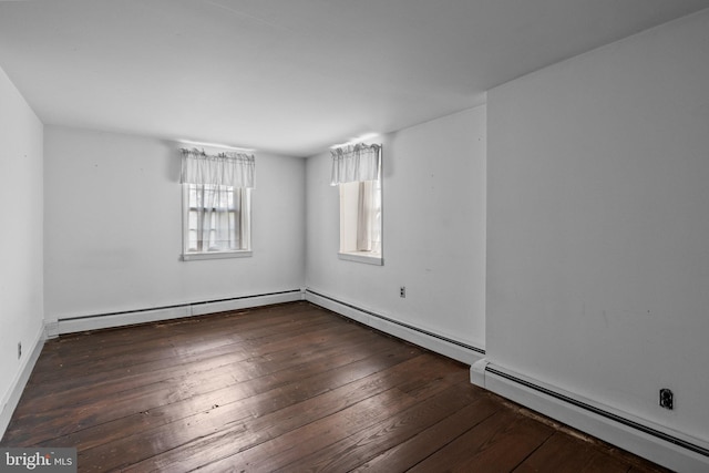 spare room featuring baseboard heating and dark wood-type flooring